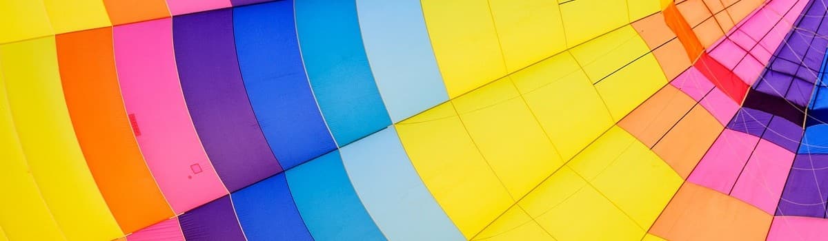 Close-up of colorful hot air balloon fabric with blue, purple, yellow, and pink stripes.